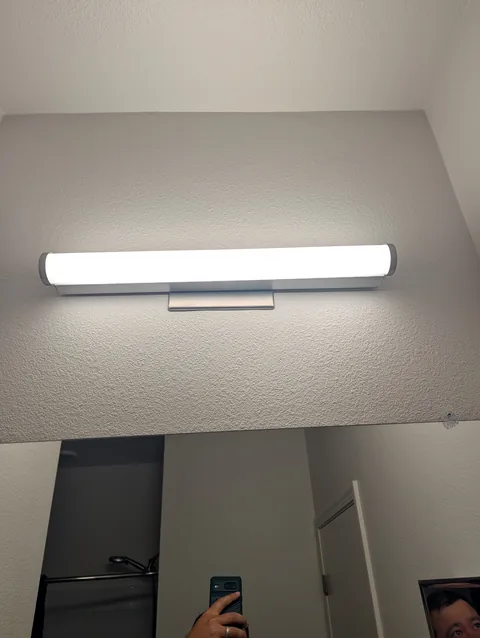 New vanity light fixture installed above a bathroom mirror