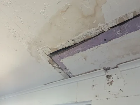 Water damaged ceiling with exposed drywall before repair